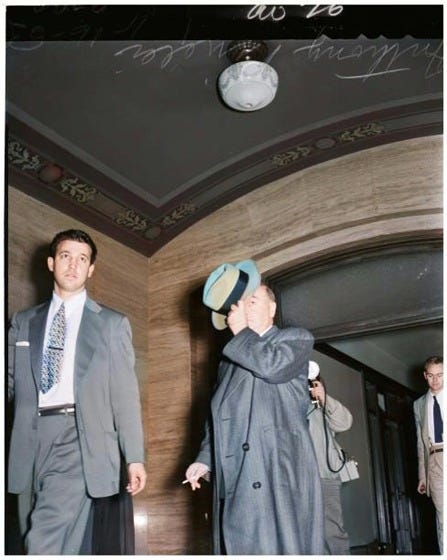 A person in a suit and tie standing in a hallway

Description automatically generated