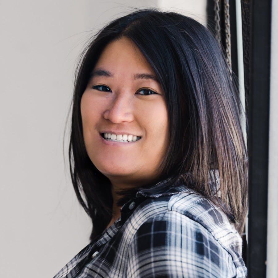 A headshot of C.B. Lee smiling, wearing a plaid shirt