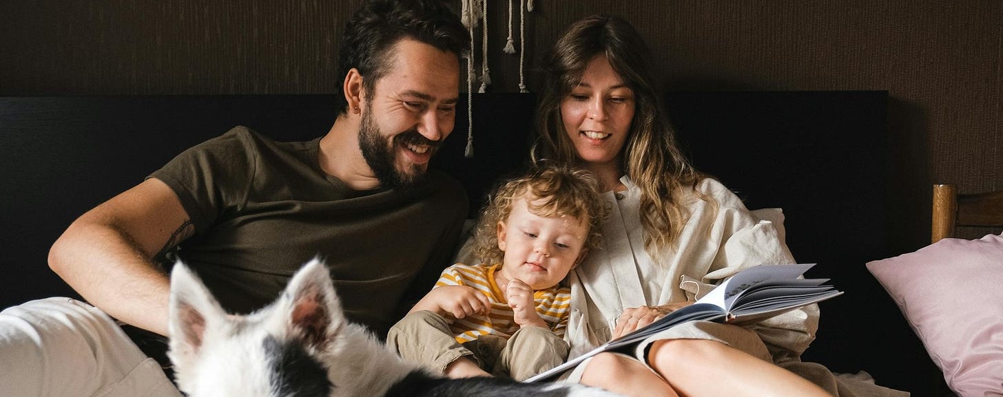A father and mother reading to their child while in the bed