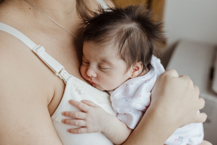A mother with an infant sleeping on her chest after nursing. A mother with an infant sleeping on her chest after nursing.