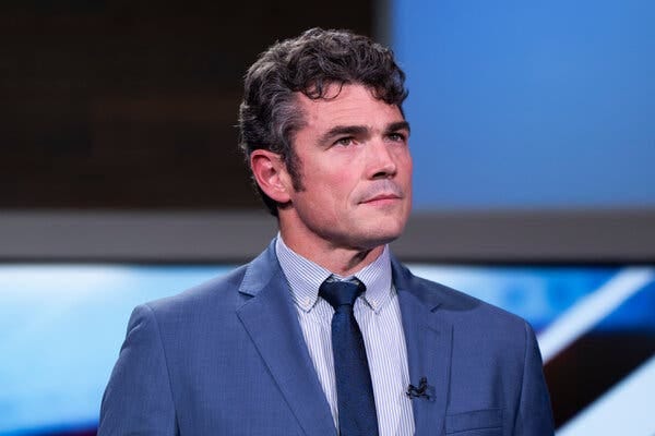 Joe Kent con traje y corbata azul.