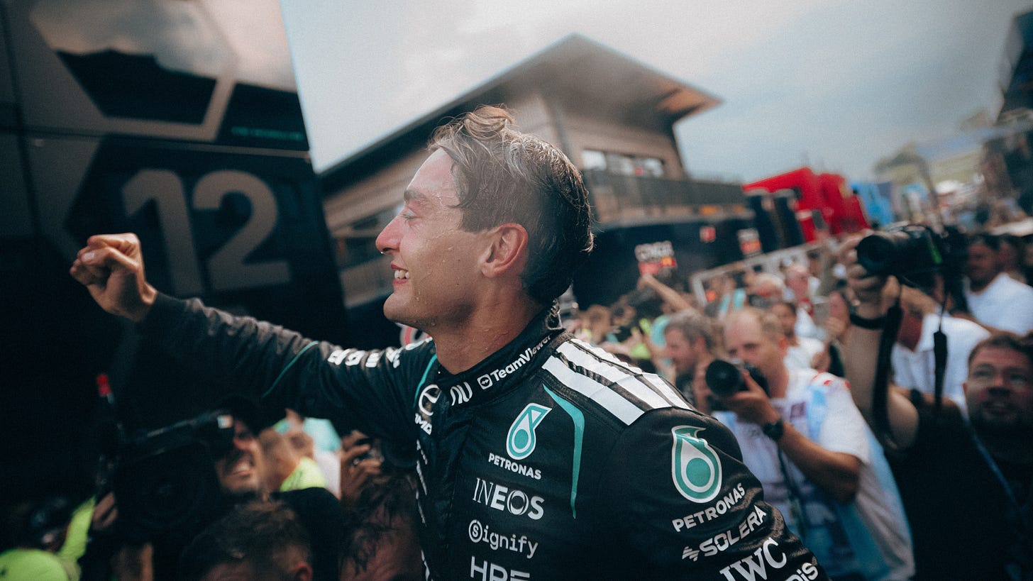 George Russell celebrates in the Austrian Grand Prix paddock with Mercedes staff as photographers capture the celebrations