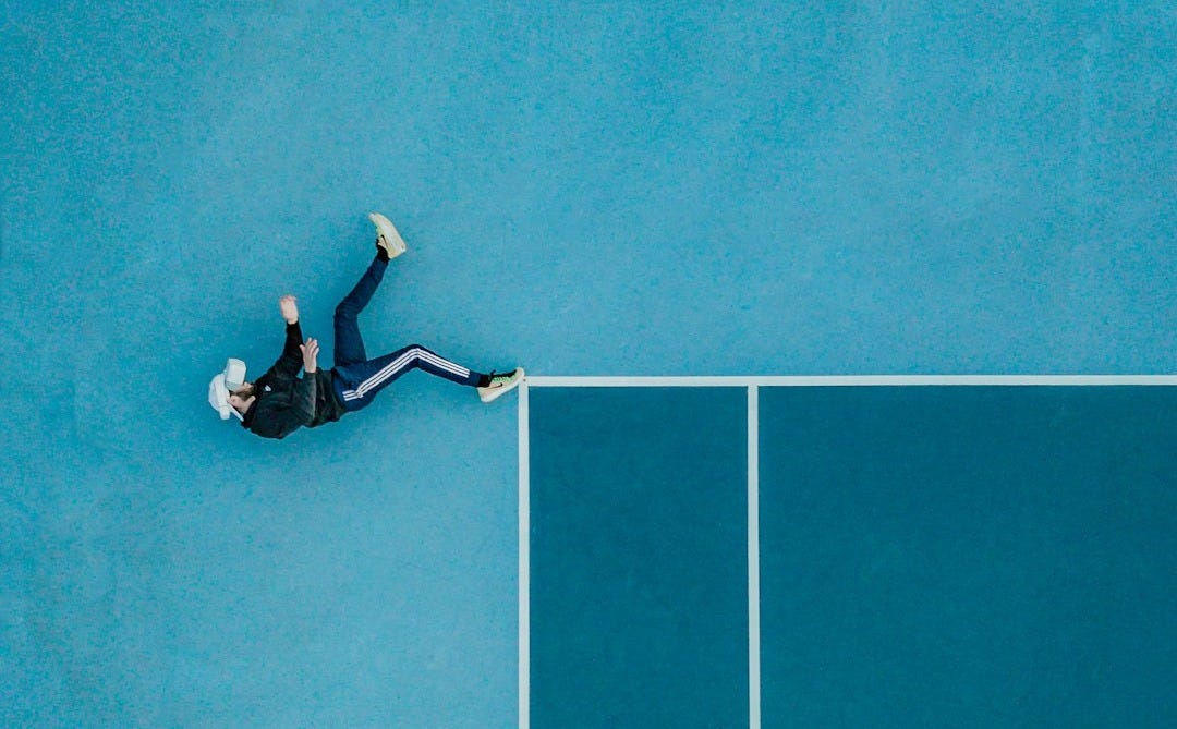 man in black shirt and black pants lying on blue floor man in black shirt and black pants lying on blue floor