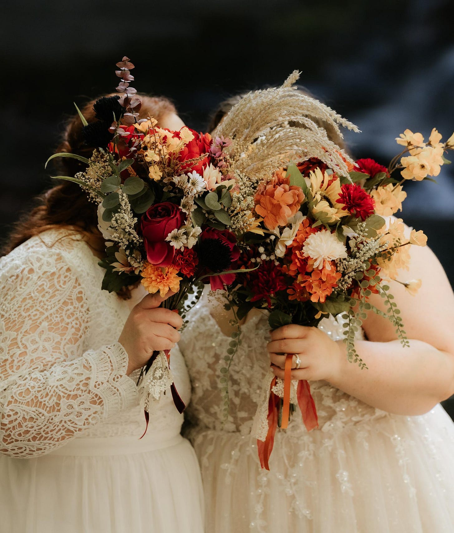 Portrait of two brides with fall bouquets covering their faces