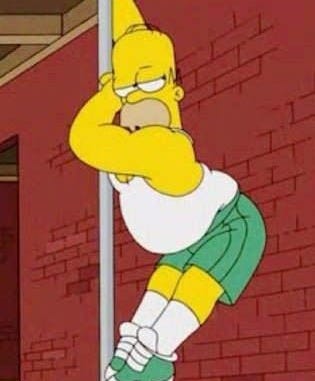This may contain: the simpsons standing on top of a box in front of a brick wall and wearing green shorts