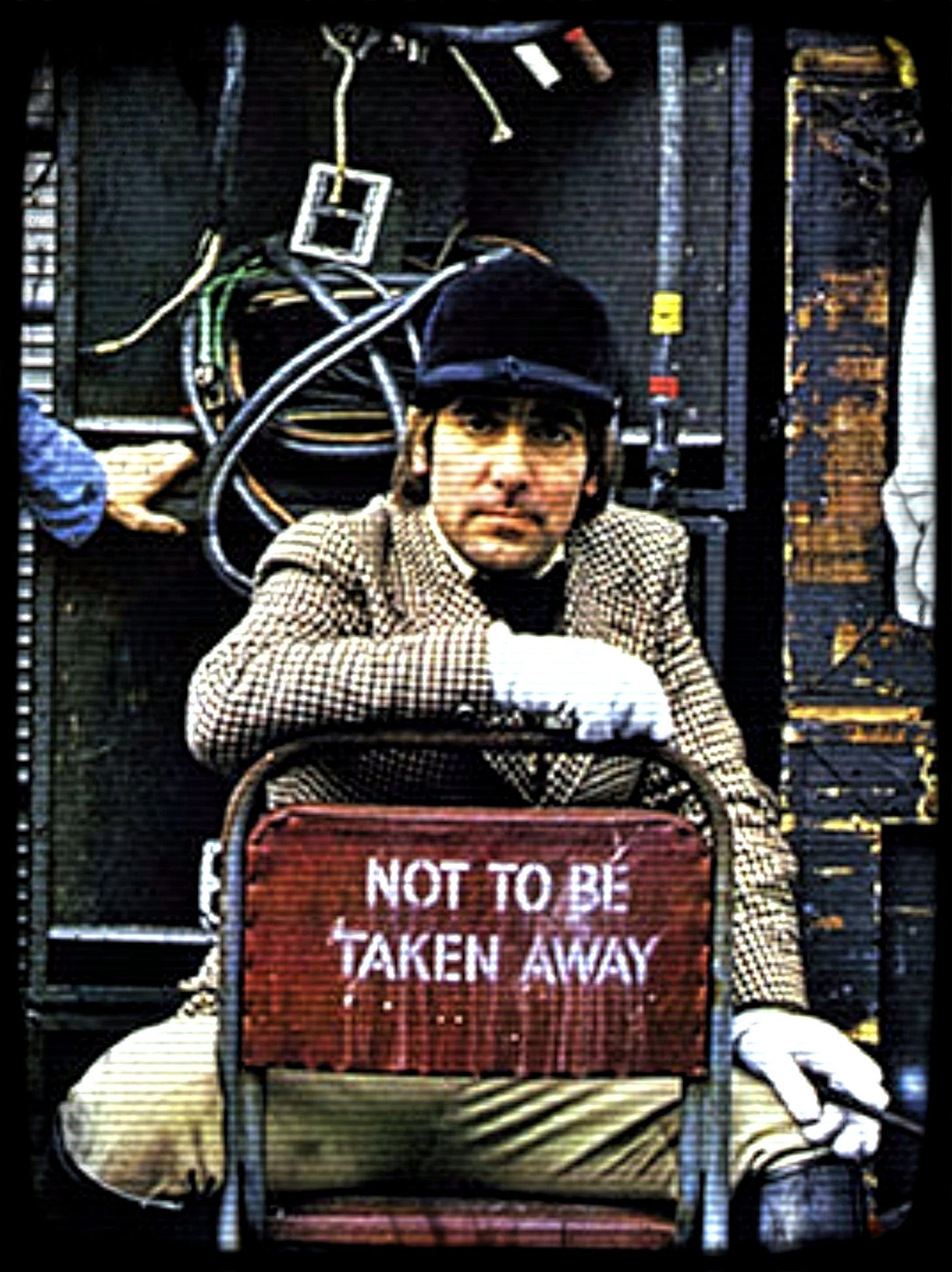 Keith Moon sitting on chair marked 'not to be taken away'.
