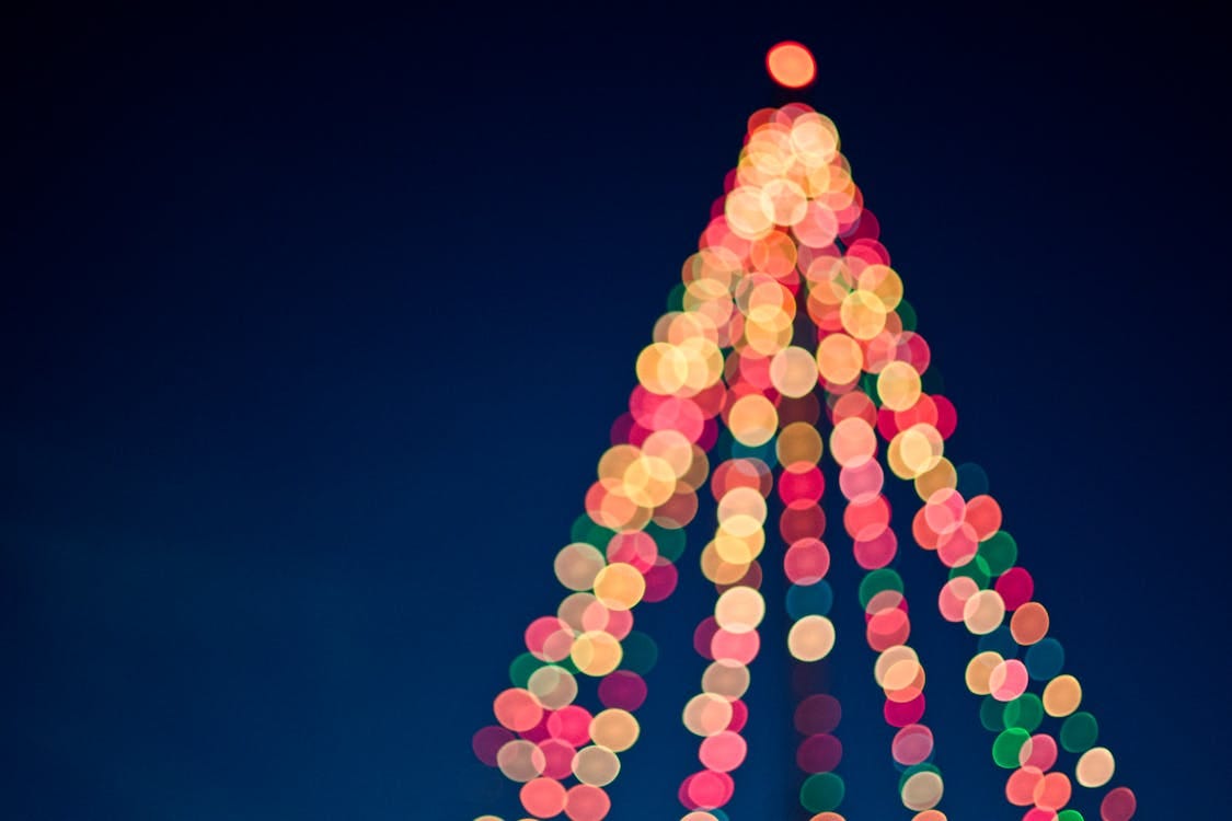 Free Colorful bokeh lights forming a Christmas tree against a dark blue sky. Stock Photo
