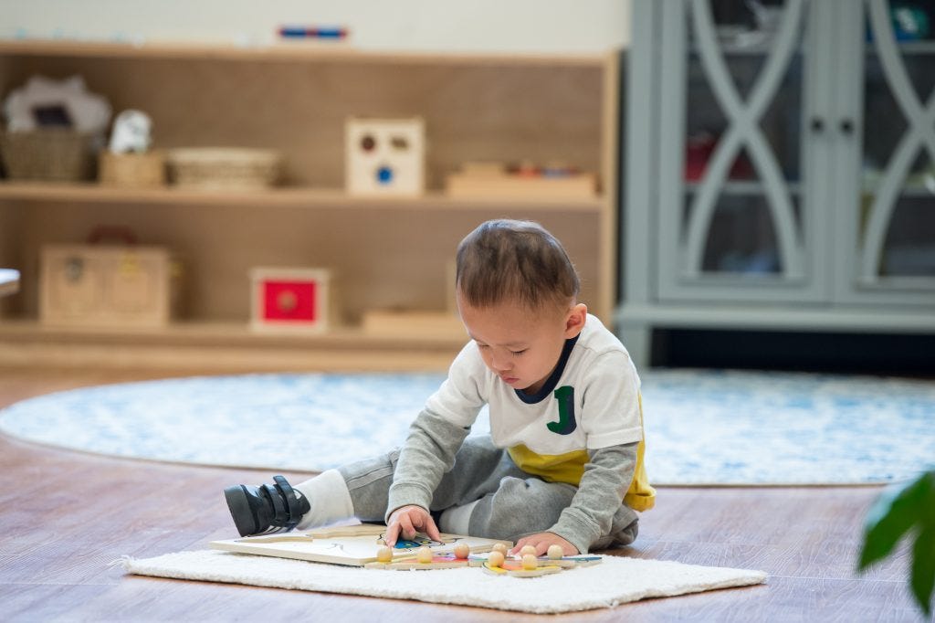 Child using Montessori puzzle material on floor mat during the Guidepost Montessori experience Child using Montessori puzzle material on floor mat during the Guidepost Montessori experience