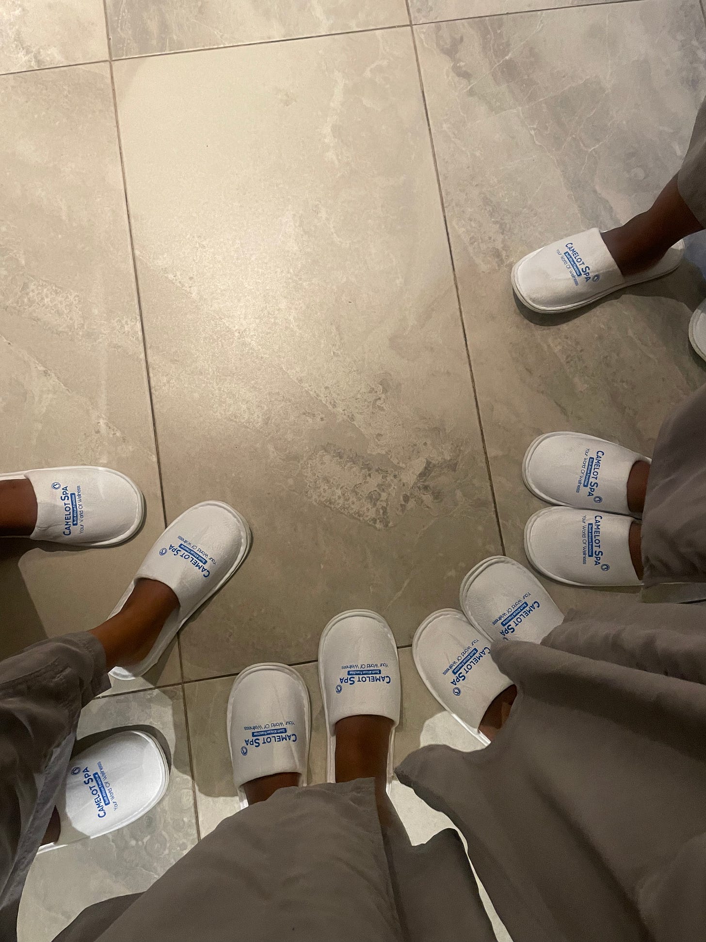 Feet of Stella and friends. They are wearing spa slippers.