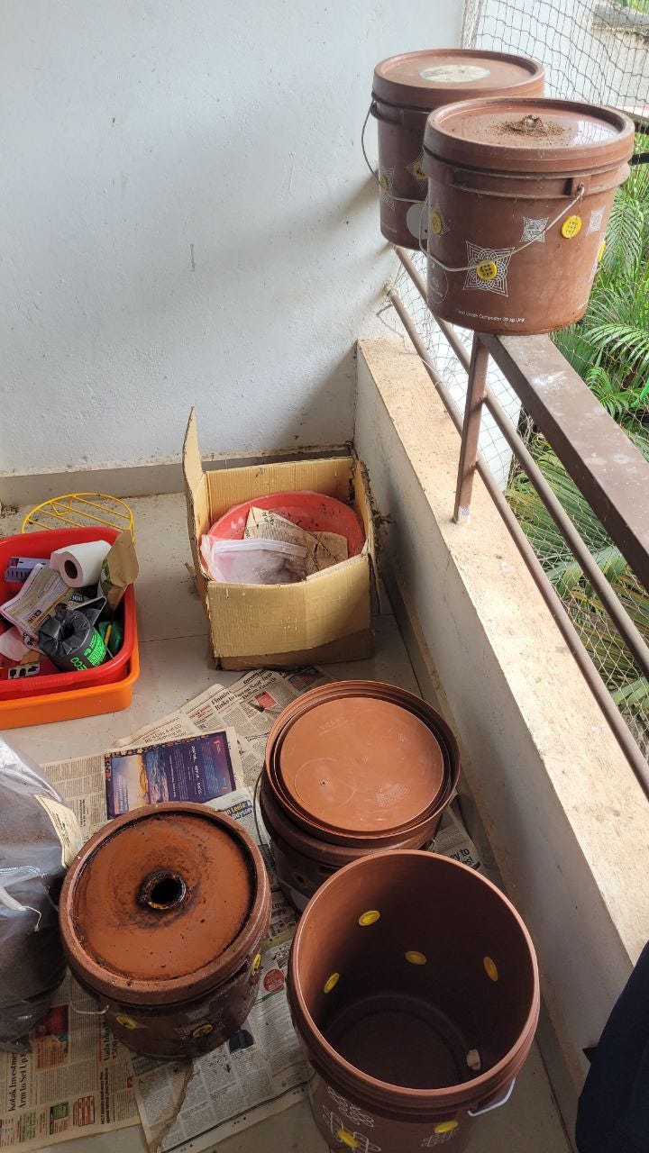 On the floor of the balcony are three boxes waiting to be tended to and on the balcony ledge are two closed boxes of compost.