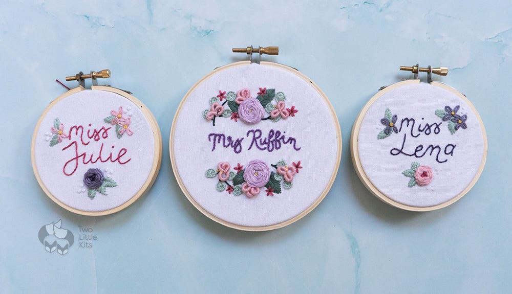 Three hand embroidery, finished pieces. Two in 3-inch hoops and one in a 4-inch hoop. The two smaller pieces read "Miss Julie" and "Miss Lena" and have small floral embellishments in pinks and purples. The larger piece reads "Mrs Ruffin" and has two semi-circles of floral embroidery work in various stitches, also in a range of pinks and purples.
