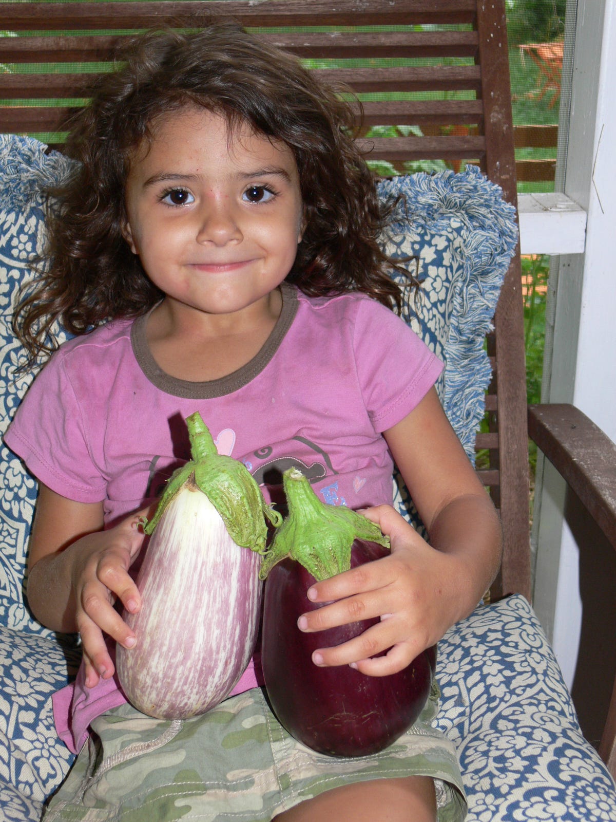 a young girl holding eggplants