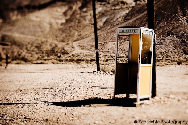 A lone phone booth in a desert landscape, symbolizing missed connection and the longing to be heard. Courtesy of Ken Gehle Fine Art landscape photography.