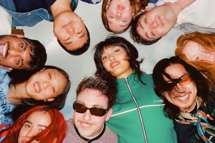 This may contain: a group of people standing in a circle with their eyes closed and one person wearing sunglasses