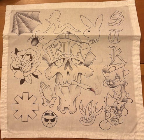 Black ink drawing on white cloth, which includes a skull smoking in the middle, surrounded by familiar logos and other designs