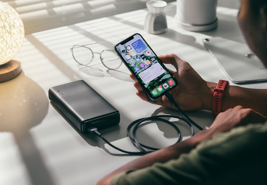 person holding black smartphone on white textile
