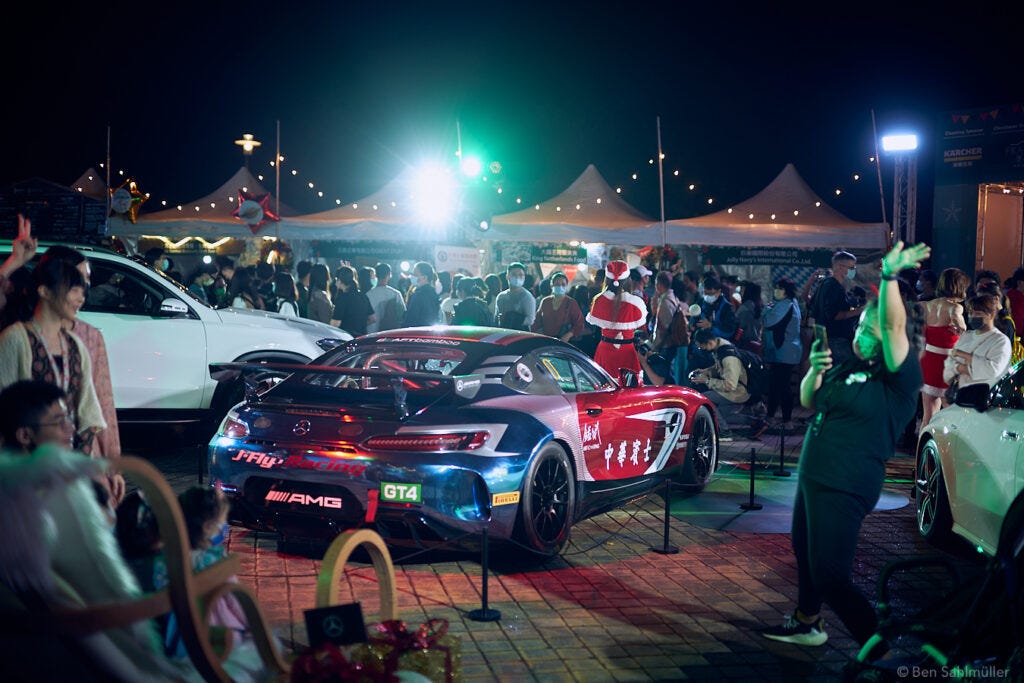 A sports car displayed at a German Christmas market in Taipei, presented by a young women in a Santa Claus costume. A sports car displayed at a German Christmas market in Taipei, presented by a young women in a Santa Claus costume.