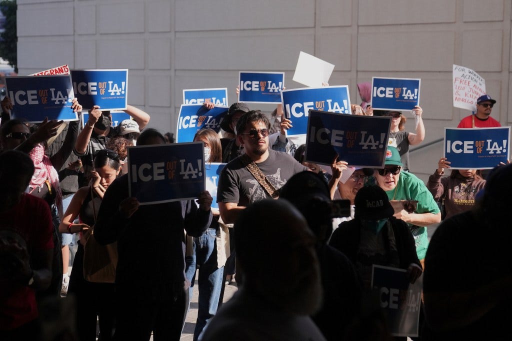 Protestors holding signs that say "ICE OUT OF LA!" at a demonstration.