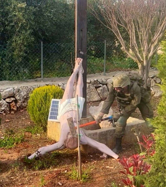 An Israeli soldier damages the head of a statue of Jesus, in Debel, southern Lebanon