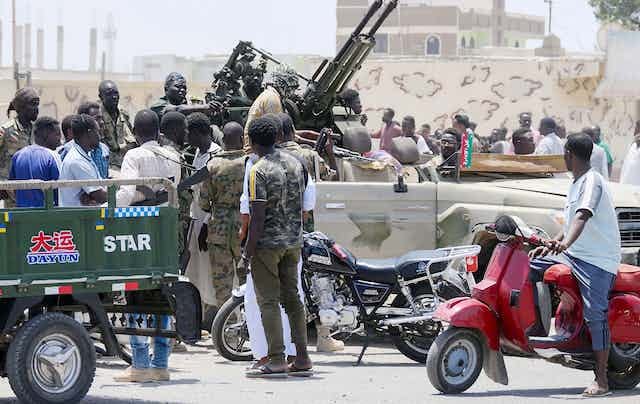Men in fatigues sit in a vehicle with heavy machine guns. Men in fatigues sit in a vehicle with heavy machine guns.