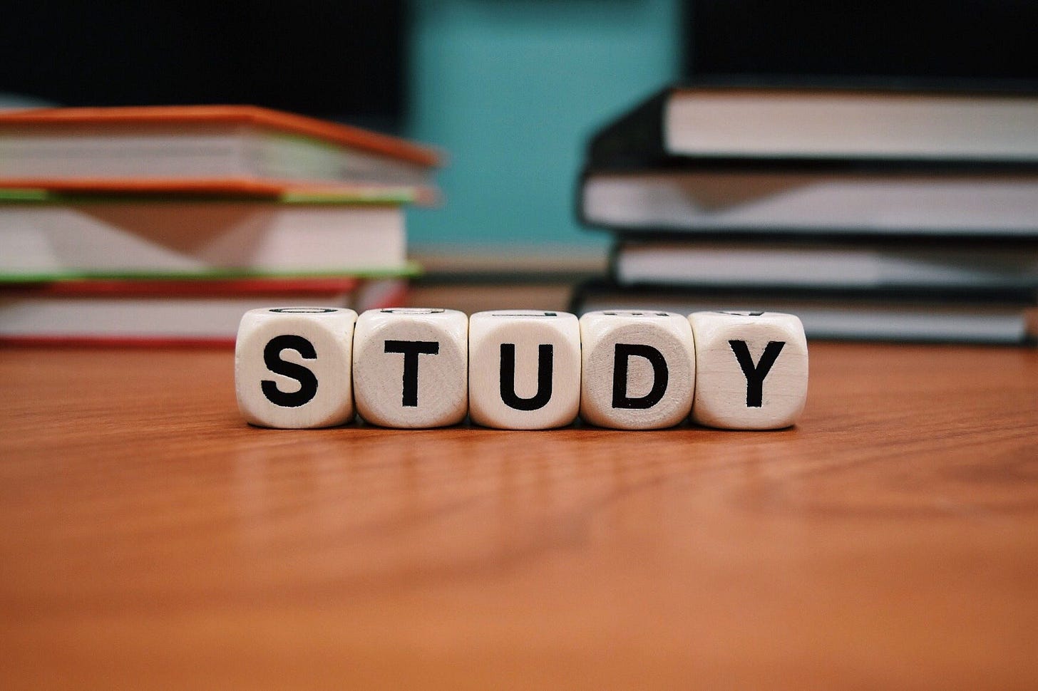 blocks on a table spelling the word "study" with books in the background