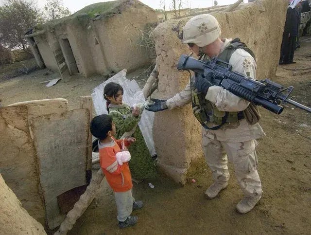A 4th Infantry Division soldier distributes gifts to children in a small village near Riyad, Iraq, in 2004, showcasing humanitarian efforts. A 4th Infantry Division soldier distributes gifts to children in a small village near Riyad, Iraq, in 2004, showcasing humanitarian efforts.