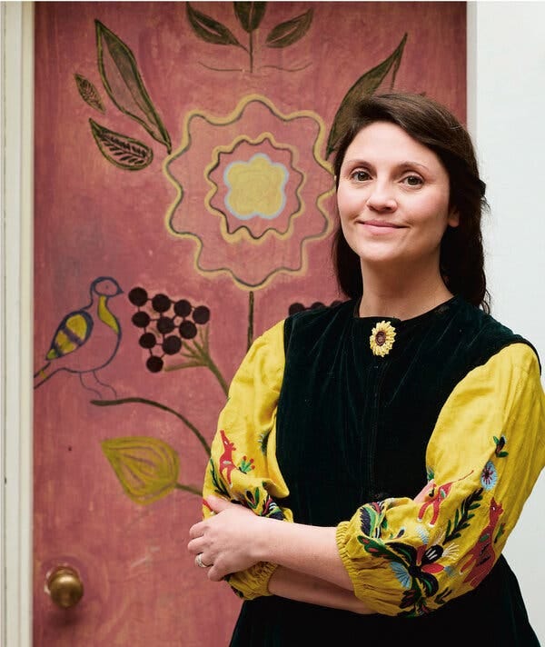 A portrait of Olia Hercules in front of a door painted pink.