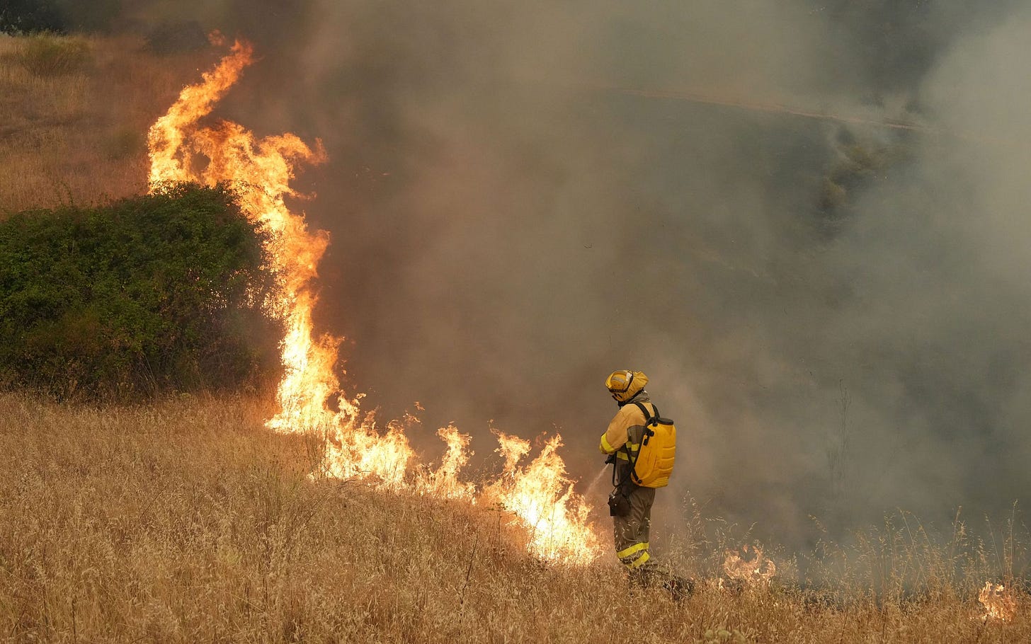 Firefighter putting out fire in field. Firefighter putting out fire in field.