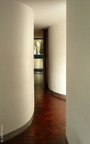 This may contain: an empty hallway with white walls and brick flooring is seen through the doorways