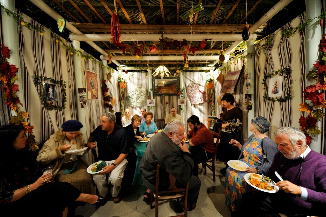 Guests eat inside an outdoor Sukkah to celebrate the Jewish holiday of Sukkot at the home of Alan a