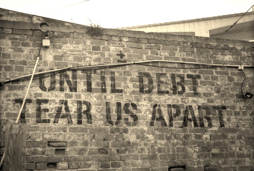 a sign on a brick wall that says until debt tears apart