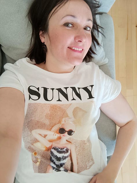 Promotional graphic showing a selection of elegant, handcrafted polymer clay earrings with gold accents and various artistic patterns. The central text reads: "GIVEAWAY – WIN FREE EARRINGS – READ CAPTION FOR RULES."  A smiling woman taking a casual selfie while lying down, wearing a white t-shirt featuring a Barbie doll graphic and text saying "SUNNY." She is wearing stylish polymer clay earrings.  Close-up image of a pair of handcrafted, textured black hoop earrings next to a sleek black jewelry box branded with gold lettering "CoruLinna DESIGN," displayed against a green and white fabric backdrop.