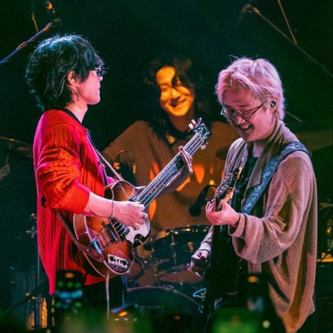 This may contain: two women standing next to each other while playing guitars and singing in front of microphones