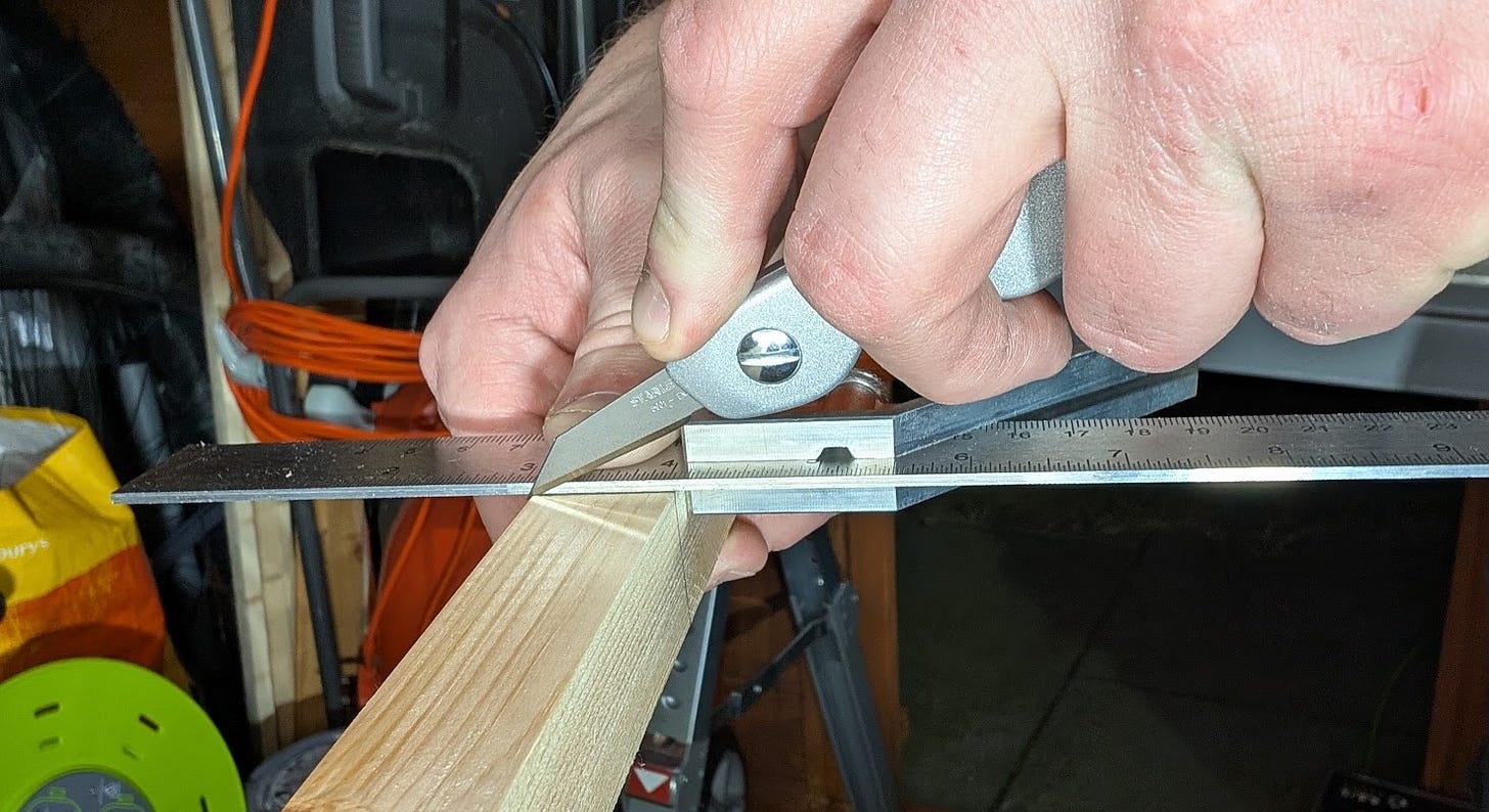 hands holding a sharp knife against a metal square to score the wood under the knife