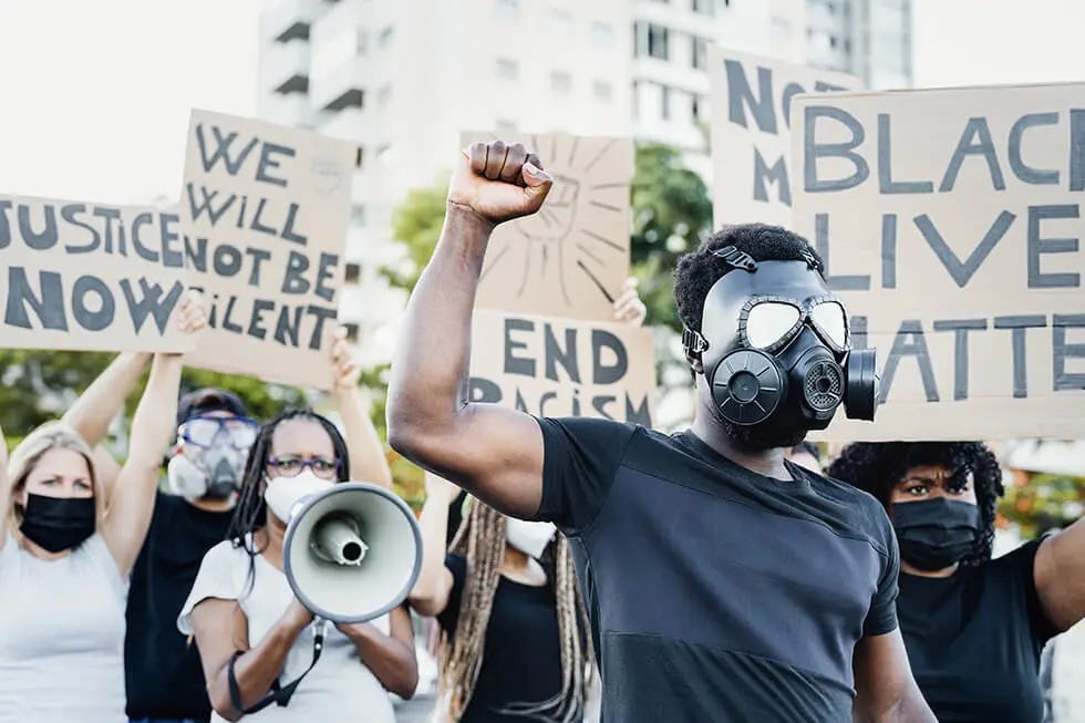 Protesters with signs advocating for justice and ending racism, some wearing masks Protesters with signs advocating for justice and ending racism, some wearing masks