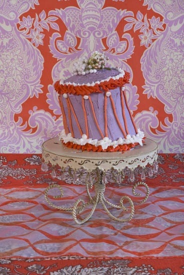 This may contain: a three tiered cake sitting on top of a table next to a red and pink wall
