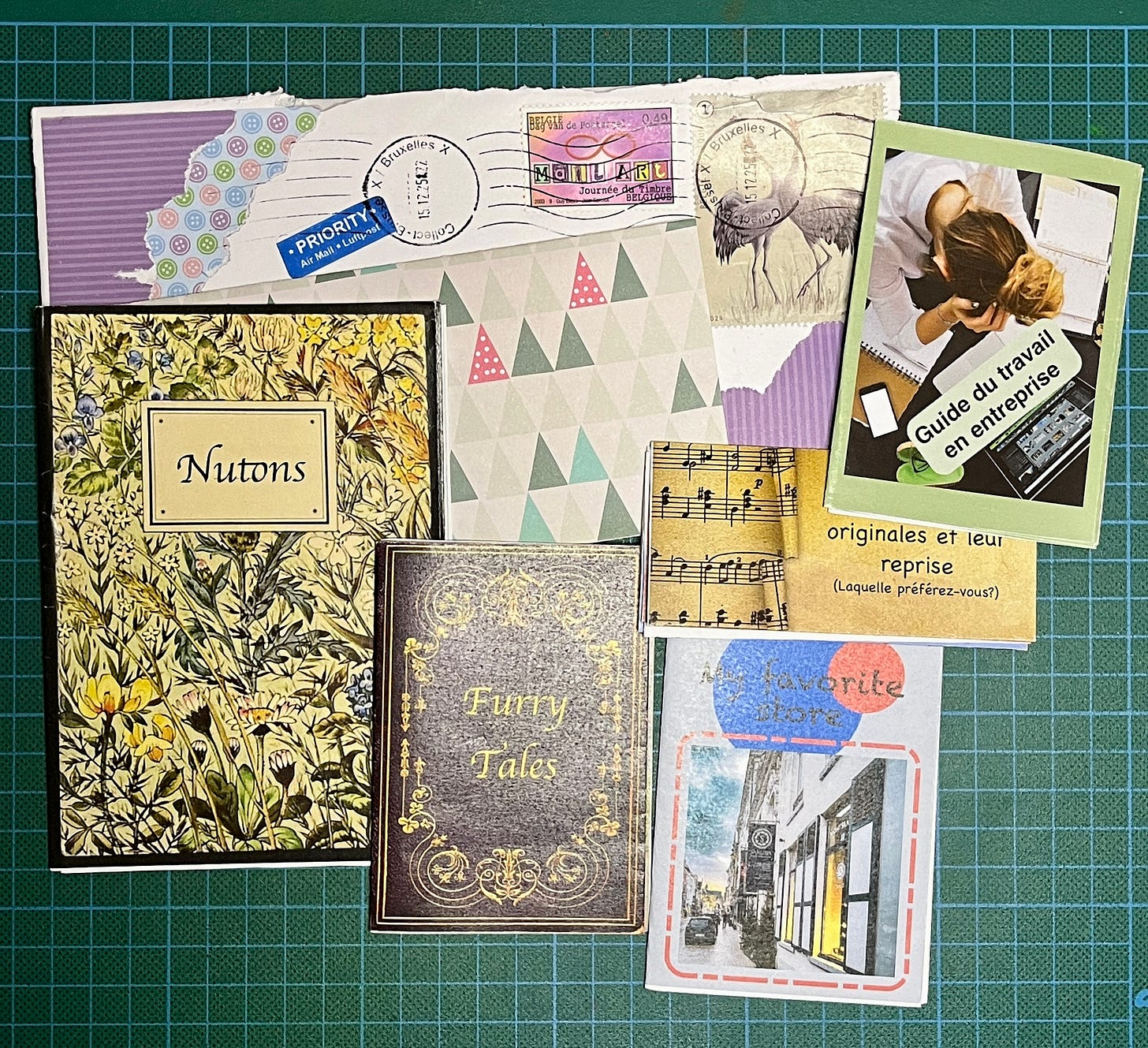 Il y a une enveloppe décoré et du papier au motif de sapins stylisés, il y a 3 mini zines, un zine format livret A5 et un petit zine de format spécial.