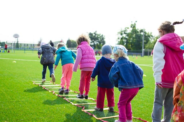 Children doing a jumping exercise on a green lawn