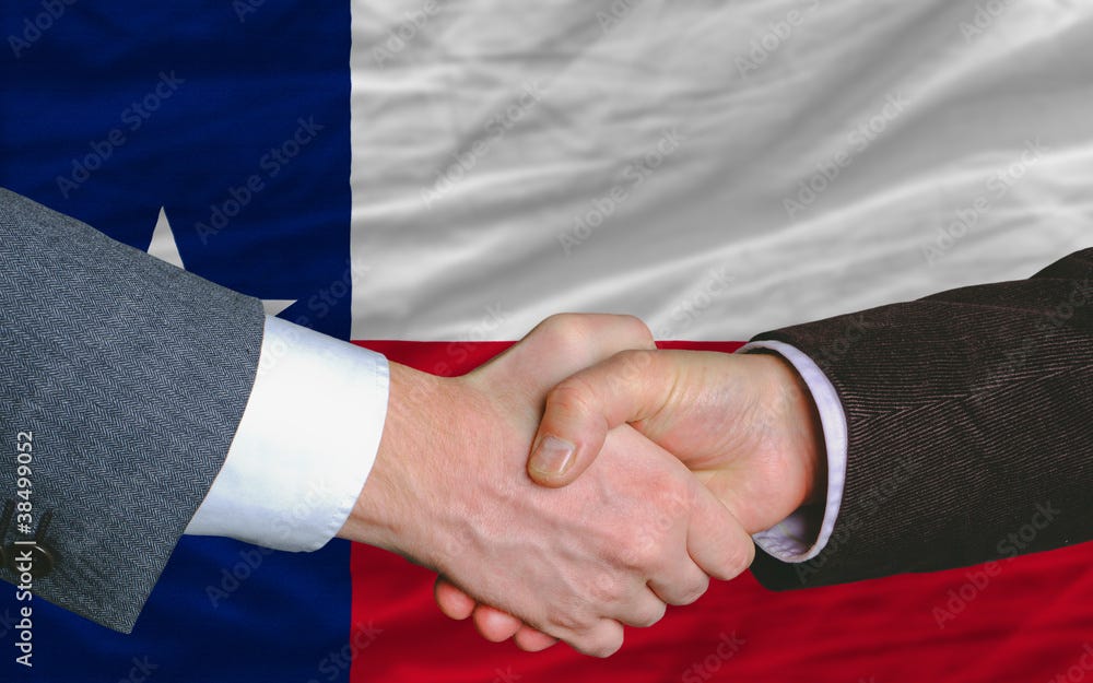 The hands of two white men shaking in front of the Texas flag