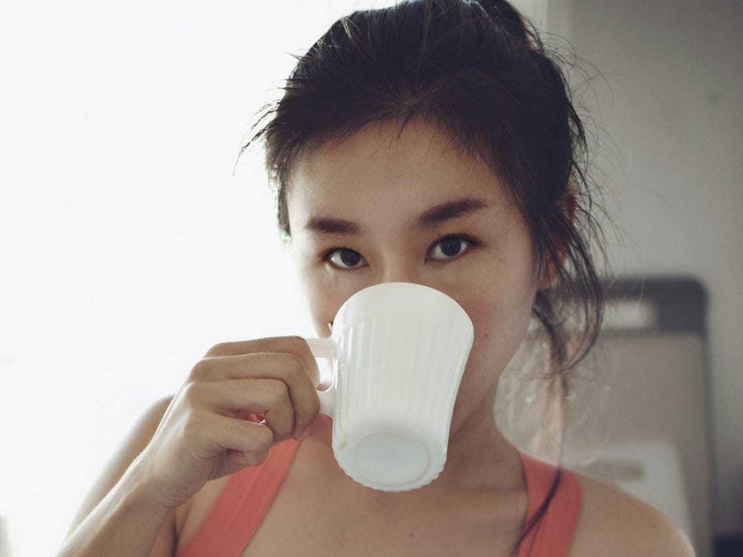 woman in red sports bra drinking from white ceramic mug