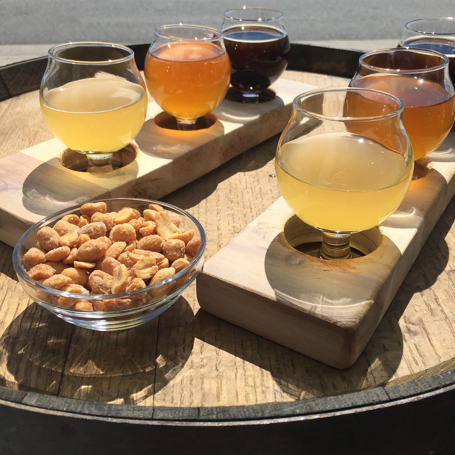 On a wooden barrel facing the street, two flights of beers ranging from golden to dark. Between them is a dish of honey roasted peanuts.