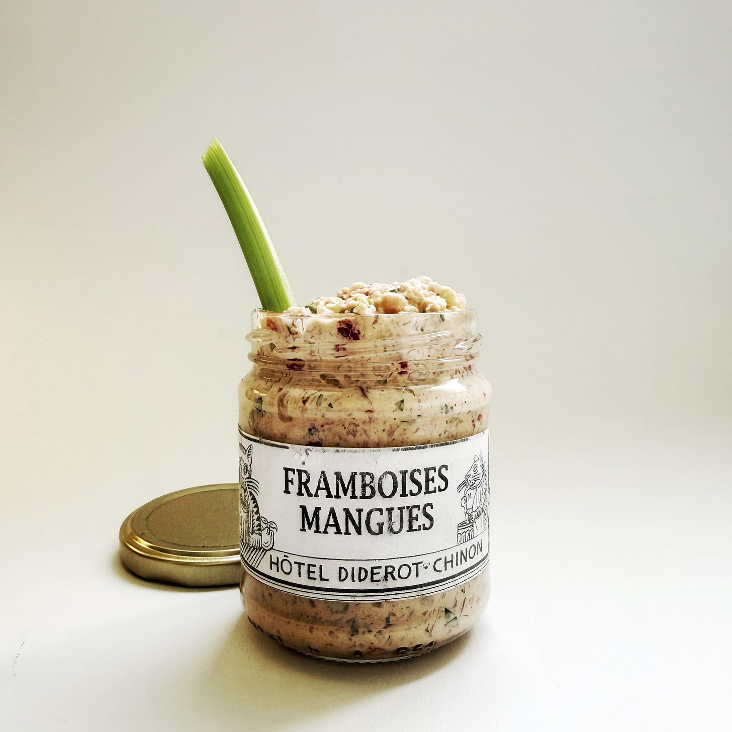 A small jam jar from a French hotel repurposed to house deviled ham. A celery stalk rises from the spicy quagmire. 