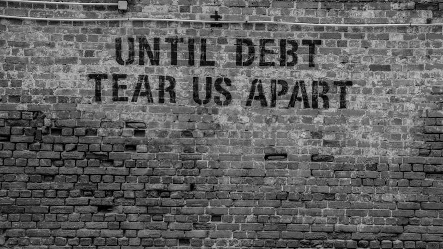 Until debt tear us apart printed red brick wall at daytime
