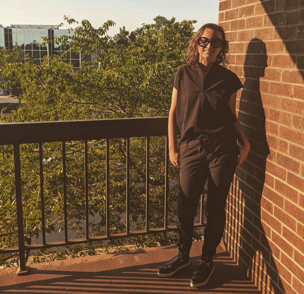 woman, shown on a balcony, in a black scrubs set from the brand FIGS woman, shown on a balcony, in a black scrubs set from the brand FIGS
