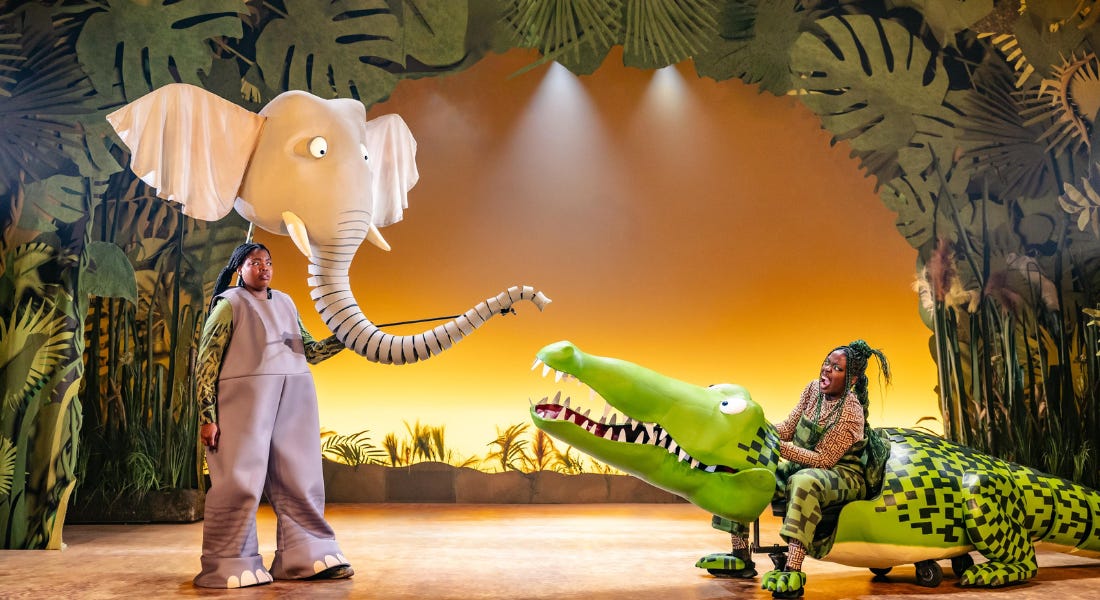Two puppet actors on stage - one with an elephant head and one with a crocodile costume