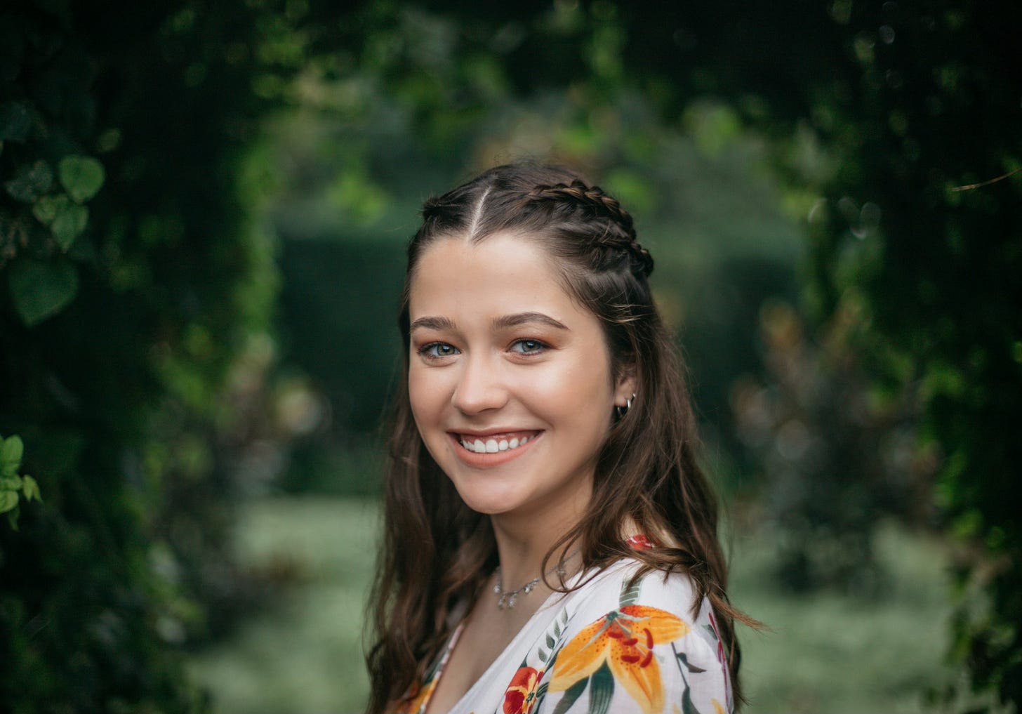 Young woman in nature with long dark hair, braided on top, smiles into the camera. Young woman in nature with long dark hair, braided on top, smiles into the camera.