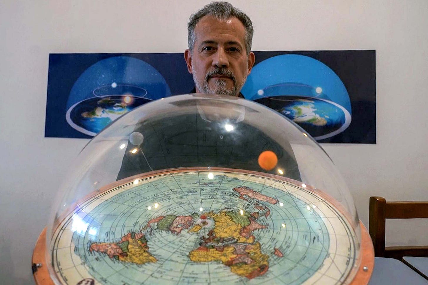 Flat-earth conspiracy theorist Anderson Neves displays a model of what he believes the planet really looks like - a dome over a flat map with moon and sun overhead. Flat-earth conspiracy theorist Anderson Neves displays a model of what he believes the planet really looks like - a dome over a flat map with moon and sun overhead.