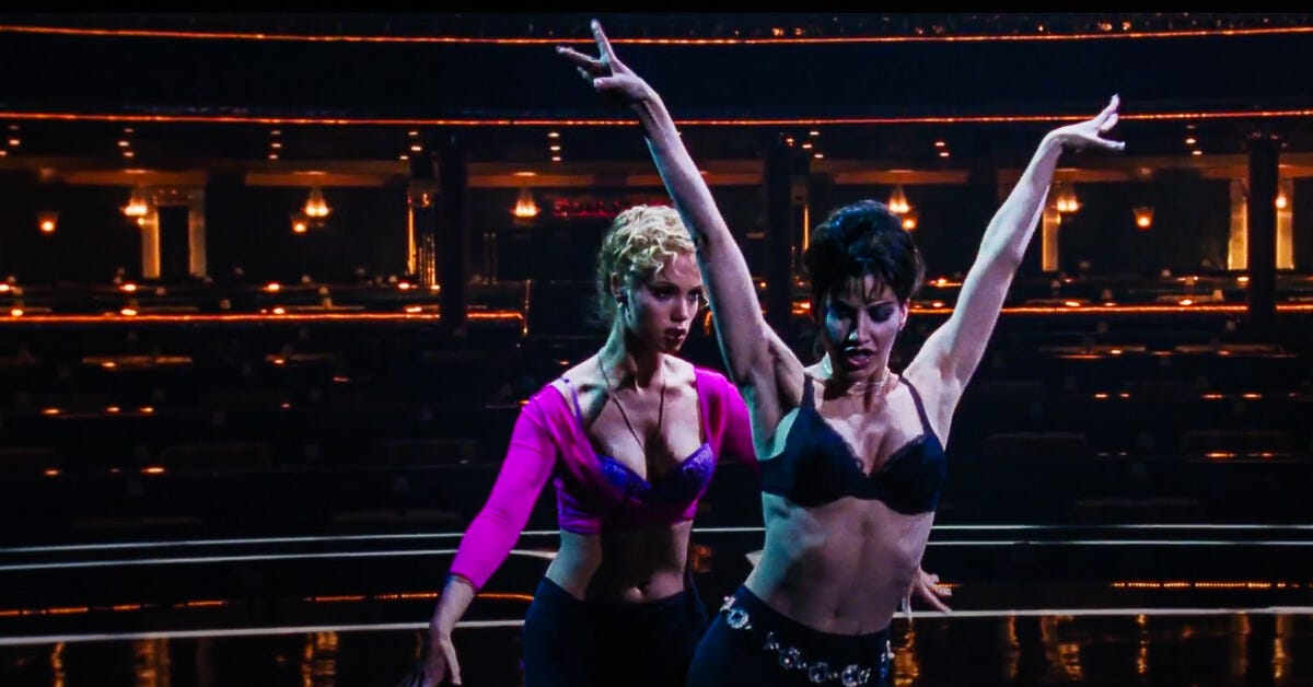 Cristal demos the show's dance moves to Nomi during a private rehearsal with the house lights dimmed on stage