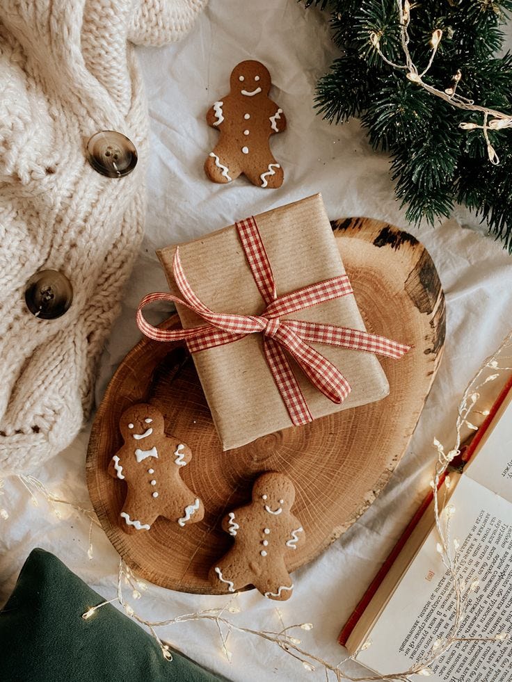 This may contain: an open book on top of a wooden plate next to christmas decorations and gingerbreads