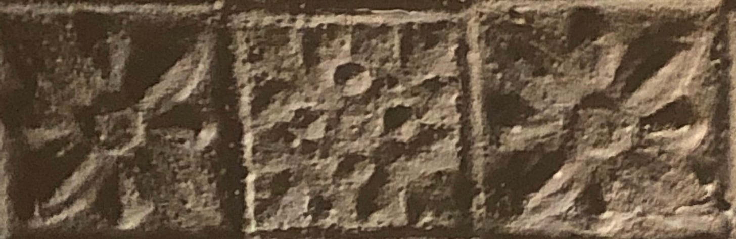 three crude squares of painted tin stamped in two patterns.
